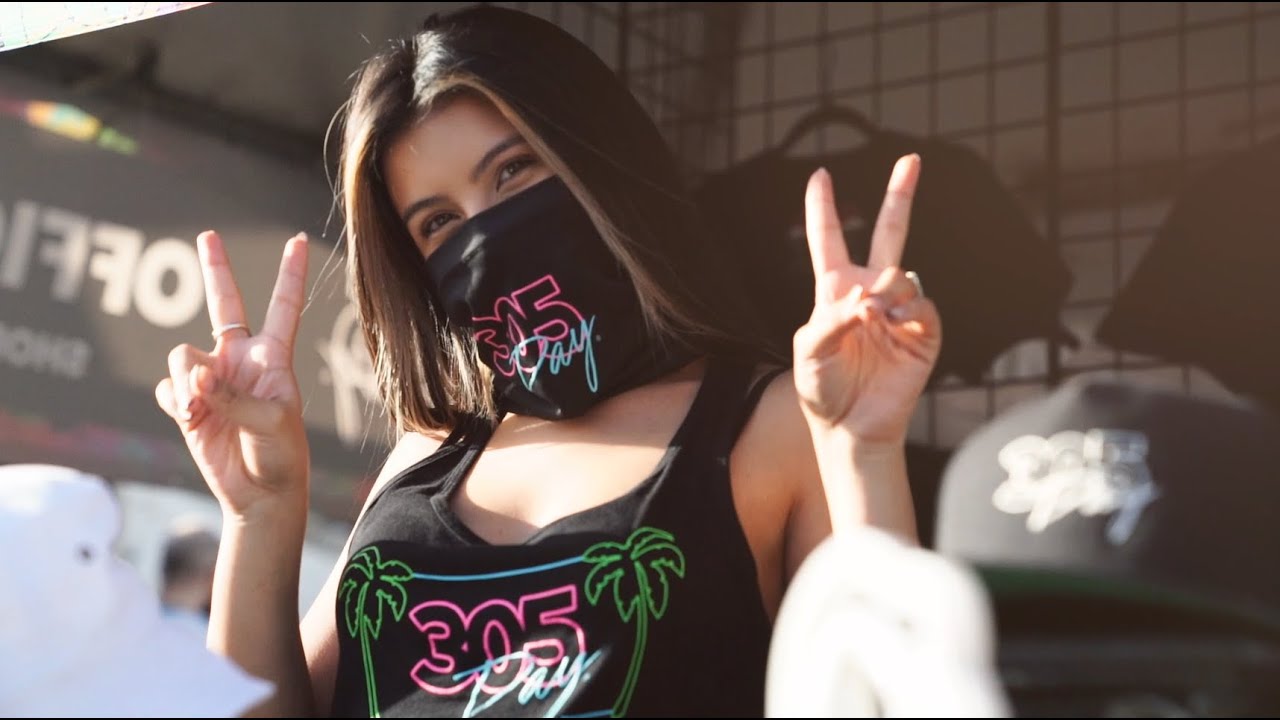 A woman posing peace sign wearing a mask with print; 305 day