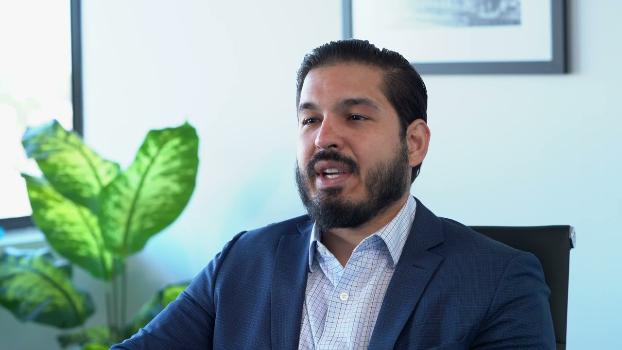 Image of a bearded man in a formal suite appears to be in an interview.