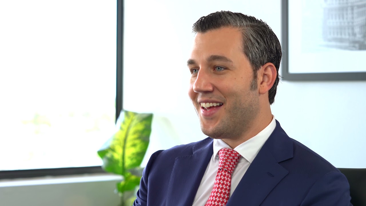 A caucasian man in a formal suite smiling during an interview of how JMM started