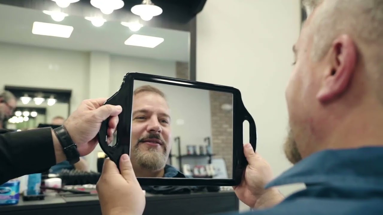 A man in a barbershop looking at himself in the mirror