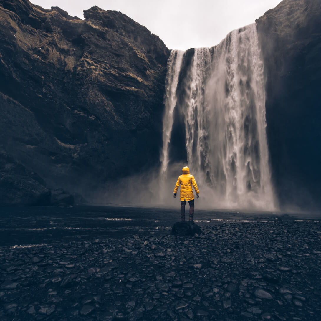 An explorer on Icelandic tour facing the beautiful waterfalls