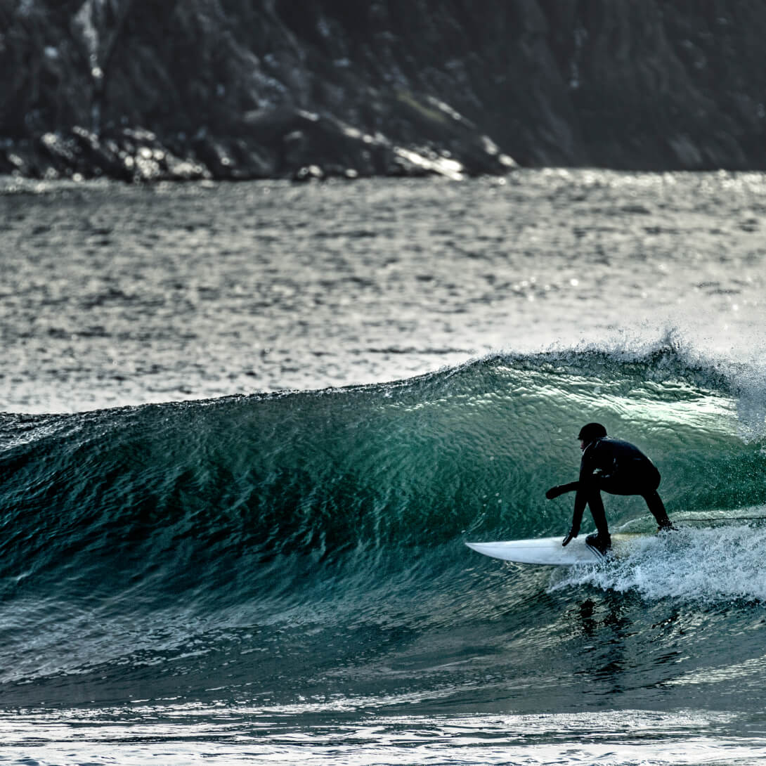 A young man surfing, riding a wave to the shore.